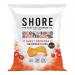 A neat stack of twenty-four compact 25g Shore Crisps pouches fills the frame; each glossy pouch displays the Shore Seaweed Chips logo and a bold red Sweet Sirarcha label. Dark green seaweed crisps peek through a clear window beside stylized ocean waves and chili illustrations soft salt-kissed sheen
