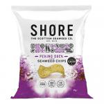 A glossy pouch of Shore Seaweed Chips sits against a neutral background. Emerald-green seaweed crisps with curled, textured edges spill beside the packet. Packaging shows ocean-blue graphics, Asian-style red and gold accents and bold brand lettering.