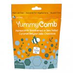 Six glossy pouches display the Yummycomb logo atop warm amber and brown packaging. Each 100g bag shows honeycomb graphics, caramel drizzle and chocolate squares with a sprinkle of sea salt. Pouches sit stacked and slightly angled, revealing resealable tops and nutrition panels. Neutral grey backdrop