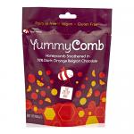 A matte pouch displays a deep brown field with bright orange accents and a clear '70% Dark' badge. Illustrated orange slices and honeycomb patterns frame the Yummycomb logo. The front lists '100g' and six matching pouches stand side by side against a neutral backdrop. Soft highlights and faint gloss