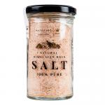A clear glass jar holds pale pink fine-grain Himalayan salt, packed near the lid. A simple white label wraps the jar with black logo text and minimal graphics. A metal screw cap seals the jar; six identical jars stand grouped on a neutral background. Soft light creates subtle reflection on the glass