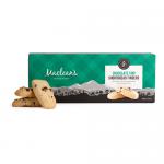 A red-and-cream box with a tartan border shows the Maclean’s Highland Bakery logo and a clear window revealing neat rows of golden shortbread fingers studded with chocolate chips. The fingers rest in a lined tray, their crumbly surface and chocolate flecks visible.