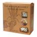 A rustic selection box sits open to reveal four artisan biscuits, each with distinct texture and shape: a golden oat round, a sugar-dusted shortbread, a seeded crisp and a chocolate-speckled sable. Crumbs scatter on a wooden board beside a linen napkin and wheat stalks, bathed in soft morning light.
