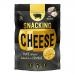 Photo shows a small round crunchy cheese crisp studded with black truffle flecks, golden-brown and textured, stacked on a dark slate beside thin charcuterie slices. A rustic Serious Pig wrapper sits partially open, its bold logo and truffle imagery visible Nearby, sliced truffle curls glint faintly