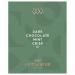 Glossy dark-green wrapper frames a slender dark chocolate bar embossed with crisp mint flecks. The label displays elegant gold lettering and subtle botanical mint illustrations. A single square is broken, revealing dense, glossy interior studded with tiny pale mint crystals. Fine ridges catch light
