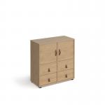 The photograph shows a sleek, modern cube storage unit standing at 875mm high. It features 2 cupboards and 2 sets of drawers, all with oak inserts. The unit is mounted on glides for easy movement. The overall look is elegant and functional, perfect for any living space.