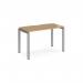The photograph showcases a sleek and modern design, featuring a Dams Bench Desking Adapt single desk. The desk has a silver frame and a smooth oak top, measuring 1200mm by 600mm. Its clean lines and minimalist style make it a stunning addition to any workspace.