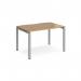 The photo shows a sleek and modern silver-framed Adapt single desk from Dams Bench Desking. The desk features a 1200mm x 800mm oak top, creating a clean and stylish workspace. Its ergonomic design ensures comfort and productivity.