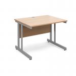 The photograph depicts a sleek and modern silver cantilever frame supporting a beech top straight desk. The desk measures 1000mm by 800mm and is designed for use in an international desking environment. The clean lines and subtle color contrast create an understated yet sophisticated look. A perfect addition to any workspace, this desk exudes professionalism and functionality.