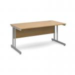 The picture shows a sleek, modern desk with a silver cantilever frame and an oak top. The desk is 1600mm long and 800mm wide, providing plenty of workspace. Its design is suitable for use in an international office setting.