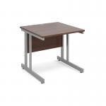 The image shows a sleek, modern desk with a silver cantilever frame and a walnut top. The desk is square and measures 800mm x 800mm, creating a compact yet functional workspace. The silver frame adds a touch of industrial style, while the warm walnut top brings a touch of sophistication to the design. This desk would be a stylish addition to any office space.