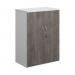 A photograph of Dams Medium Cupboards shows a sleek, white double door cupboard standing at 1090mm high. The doors have a modern touch with grey oak accents. Inside, there are two shelves for storage. This piece exudes simplicity and sophistication.