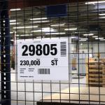 This image shows a durable sign with clear A4 pockets hanging from wire, ideal for organizing and displaying important documents in a warehouse setting. The sleek and sturdy design can withstand daily use and ensures documents stay secure.