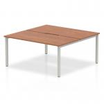 The Dynamic Bench Desking Evolve Plus 1600mm B2B 2 Person Office Bench Desk features a sleek and modern design with a walnut top and silver frame. Two people can comfortably work side by side on this spacious desk. It exudes professionalism and efficiency.