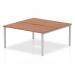The Dynamic Bench Desking Evolve Plus 1600mm B2B 2 Person Office Bench Desk features a sleek and modern design with a walnut top and silver frame. Two people can comfortably work side by side on this spacious desk. It exudes professionalism and efficiency.