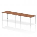 This picture features a sleek and modern Dynamic Bench Desking Evolve Plus with a 1600mm single row, perfect for two people to work side-by-side. The desk has a beautiful walnut top and a clean white frame, creating a professional and stylish office space.