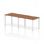 A sleek and modern office setup, this photo features a Dynamic Bench Desking Evolve Plus 1200mm Single Row 2 Person Office Bench Desk in walnut with a white frame. The clean lines and ample workspace make this desk perfect for a collaborative environment.