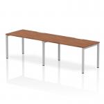 This picture features a modern and functional office set-up with the Dynamic Bench Desking Evolve Plus 1400mm Single Row 2 Person Office Bench Desk. It boasts a sleek silver frame and a beautiful walnut top, providing the ideal workspace for two individuals.