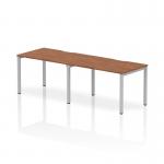 This image shows a sleek and modern 1200mm single row 2 person office bench desk with a walnut top and silver frame. The dynamic design allows for a comfortable and stylish workspace for two individuals.
