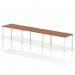 The photograph features a sleek and modern work space with a single row of three person office bench desks. The desks have a rich walnut top and are supported by a clean, white frame. The overall design exudes functionality and style, perfect for a dynamic work environment.