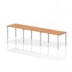 The photo shows a sleek, modern office space with a 1200mm single row dynamic bench desking setup. The oak top and silver frame contrast nicely with the surrounding decor. Three people can comfortably work at this desk, promoting collaboration and productivity.