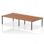 This photograph captures a modern office setup with four people working at a spacious 1600mm bench desk. The desk features a sleek walnut top and a sturdy black frame, making it a stylish addition to any workplace. The dynamic design allows for collaborative work and efficient use of space.