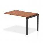 This photograph captures the sleek and functional design of the Dynamic Bench Desk Add On Units Evolve Plus. 1200mm Single Row Office Bench Desk Ext Kit in a rich walnut top and black frame. The versatile desk provides ample workspace for any office setting.