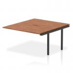 This picture shows a stylish and modern office setup with Dynamic Bench Desk Add On Units from the Evolve Plus series. The 1400mm B2B Office Bench Desk Ext Kit features a walnut top and sleek black frame, adding functionality and sophistication to any workspace.