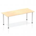 The image shows a long, rectangular table with a maple wood top and silver metal legs. The table has a sleek, modern design and appears to be sturdy and well-crafted. The silver post legs add a touch of elegance to the otherwise simple and functional table.