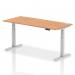 This photo shows a sleek and modern office desk with a beautiful oak top and silver legs. The desk is 1800 x 800mm and has cable ports for easy organization. It is also height adjustable, allowing for a comfortable and dynamic sitting or standing experience. Perfect for any office space.
