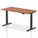 The picture shows a sleek and modern office desk with a walnut top and black legs. The desk is 1600 x 800mm and features a height adjustable design, allowing for both sitting and standing positions. It also has built-in cable ports for organization and convenience.