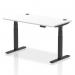 The photograph shows a sleek and modern office desk with a white top and black legs. The desk measures 1400 x 800mm and is equipped with cable ports for a clean and organized workspace. It can be easily adjusted for sitting or standing positions, making it a versatile and ergonomic choice for any office.