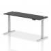 This picture features a spacious black top desk with silver legs. The desk is 1800 x 600mm and can be easily adjusted in height. There are also built-in cable ports to keep cords organized and out of the way. Perfect for a modern and functional office space.