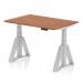 The photograph captures a modern and efficient workplace with a dynamic sit stand and height adjustable desk. The desk features a 1200 x 800mm walnut top and silver legs, with a piste foot for added stability. The clean and sleek design offers versatility for different working styles and activities.