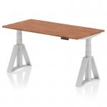 The image shows a spacious and modern workplace with a versatile and ergonomic desk. The desk features a walnut top and silver legs, with a unique piste foot for added stability. The desk can be easily adjusted to your desired height, promoting a dynamic and comfortable working environment.