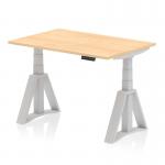 This photograph shows a sleek and modern office desk with a dynamic sit-stand feature. The desk has a maple top and silver legs, with adjustable height options. The unique Piste Foot adds a stylish touch to this functional desk.