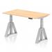 The picture shows a compact and modern office desk measuring 1400 x 800mm, with a sleek maple top and silver adjustable legs. The desk also features a dynamic sit-stand function and a piste foot for added comfort. Perfect for creating a versatile and ergonomic work space.