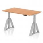 This picture shows a stylish Oak top office desk with a Silver leg and Piste Foot. The desk is 1400 x 800mm in size and is height adjustable, allowing for optimal comfort and productivity while working. The dynamic sit stand feature makes it easy to switch between sitting and standing positions throughout the day. The modern design adds a sleek touch to any office space.