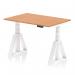 The photograph shows a modern and sleek Dynamic Sit Stand and Height Adjustable Desk measuring 1200 x 800mm. The desk features an oak top and white legs with a Piste Foot for stability. The design is minimalistic and functional, perfect for any office setting.