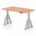 The picture shows a modern and versatile office desk that can be set to different heights for sitting or standing. It has a 1400 x 800mm beech top and features cable ports for organized wiring. The silver legs and piste foot add a sleek touch to the overall design.