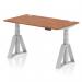 The picture shows a modern office desk with a walnut top and silver legs. It has the dimensions of 1400 x 800mm and features a dynamic sit-stand function, allowing for adjustable height. The desk also includes built-in cable ports and a unique piste foot design, providing additional support and stability.