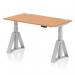 This picture features a dynamic sit stand and height adjustable desk with a 1400 x 800mm oak top, cable ports, and a sleek silver leg design. The desk also includes a piste foot for added stability and functionality.