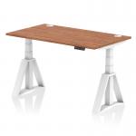 A sleek and modern office desk, the Dynamic Sit Stand and Height Adjustable Desk features a large Walnut top and white adjustable legs. With built-in cable ports and a Piste foot, this desk offers versatility and ergonomic support for any workspace.