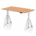This picture shows a sleek and modern office desk with a natural oak top and white legs. The desk is 1400 x 800mm and features a dynamic sit stand option for adjustable height. It also includes convenient cable ports and a unique piste foot design.