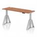 The image shows a sleek, modern office desk with a walnut top and silver legs. The desk is height adjustable and also features a dynamic sit-stand feature. It measures 1600mm by 600mm and has built-in cable ports for easy organization. The unique Piste Foot adds a touch of style and functionality to this versatile desk.