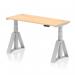 This picture features a modern and ergonomic dynamic sit stand desk. The desk has a maple top and a silver leg with a piste foot for stability. It also has cable ports for a clutter-free workspace. The desk measures 1400 x 600mm and is height adjustable for versatile use. Perfect for a comfortable and efficient office setup.