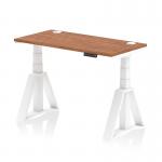 This photograph features a sleek, modern office desk in walnut with a white adjustable leg and cable ports. The desk is 1200 x 600mm and has a dynamic sit-stand feature, as well as a piste foot for added stability. It is perfect for creating a versatile and organized workspace.