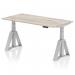 The photograph captures a sleek and modern office desk measuring 1600 x 800mm. Its grey oak top contrasts beautifully with the silver legs and features convenient cable ports for a clutter-free workspace. The desk also boasts a dynamic sit-stand function and a piste foot, perfect for those who value ergonomics and productivity in a stylish package.