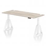This photo shows a modern and versatile office desk that can be easily adjusted for sitting or standing positions. Its grey oak top is complemented by white legs and features cable ports and a unique piste foot for added support.