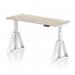 This picture features a modern office desk with a grey oak top and white legs. The desk is equipped with cable ports and a piste foot for added convenience. Its height can be easily adjusted, making it suitable for both sitting and standing positions. Its dimensions are 1400 x 600mm.